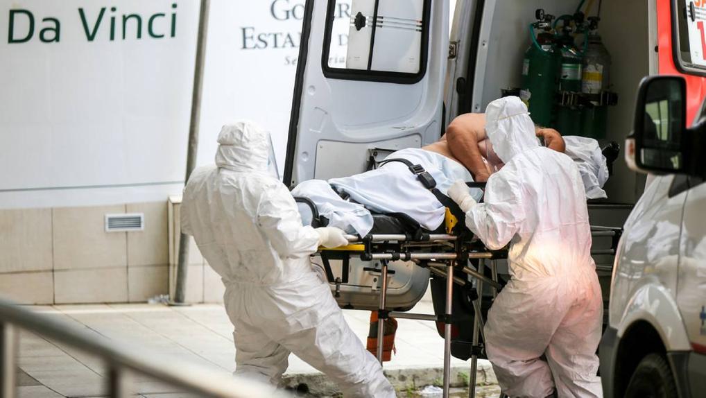 Maqueiros paramentados retiram paciente de ambulância no hospital Leonardo da Vinci em 26/05/2020