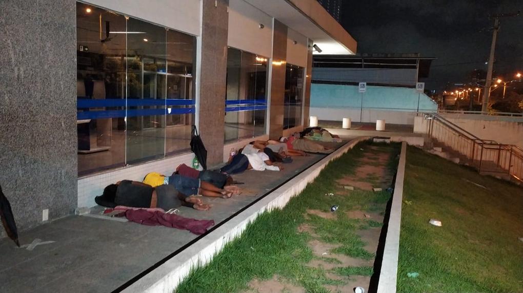 Pessoas dormindo na calçada de agência da caixa em Fortaleza
