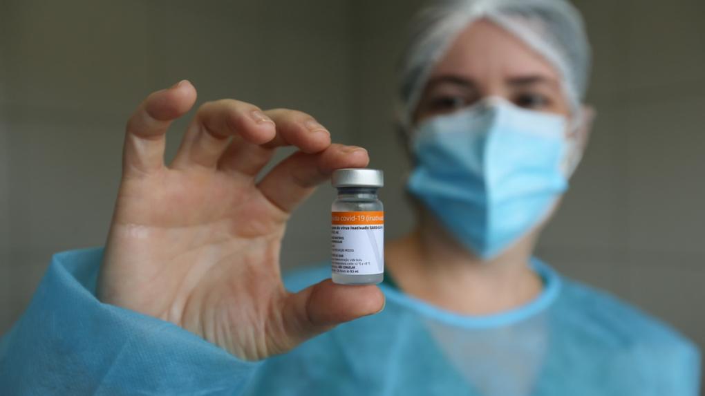 profissional da saúde exibe frasco da vacina coronavac