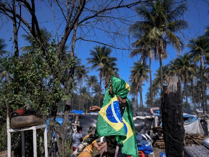 Menina enrolada em bandeira do Brasil em meio à pobreza