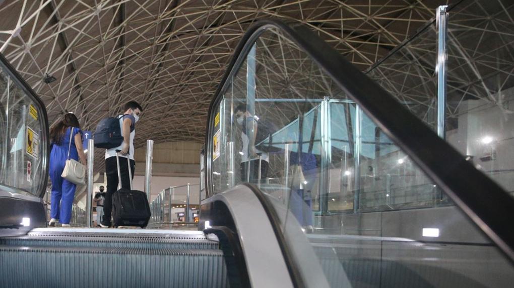 Viajantes com bagagens saindo de escada rolante no Aeroporto de Fortaleza
