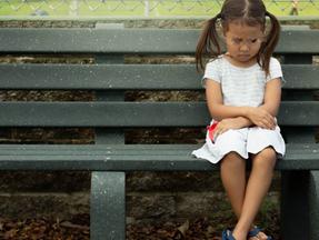 Menina triste sentada em banco