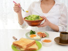 Mulher comendo salada, pães, ovo, café