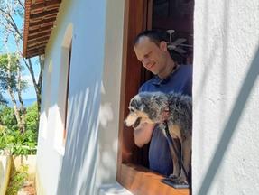 Alexandre Rossi e Estopinha na janela de uma casa