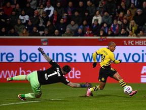 Atleta do Borussia Dortmund driblando o goleiro e chutando a bola