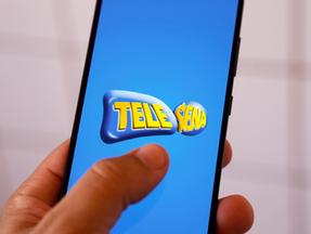 Mão segura celular aberto no aplicativo da Tele Sena