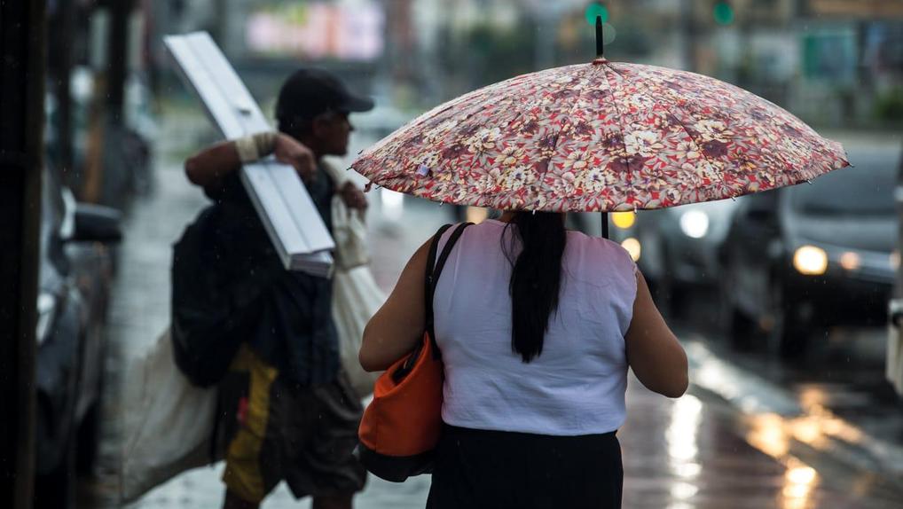 Mulher segura guarda chuva em rua de Fortaleza
