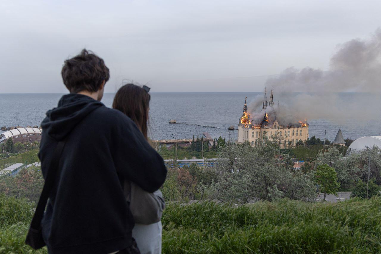 pessoas observam castelo pegando fogo