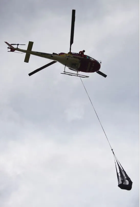 Helicóptero tira da lama o corpo de uma das vítimas da tragédia.