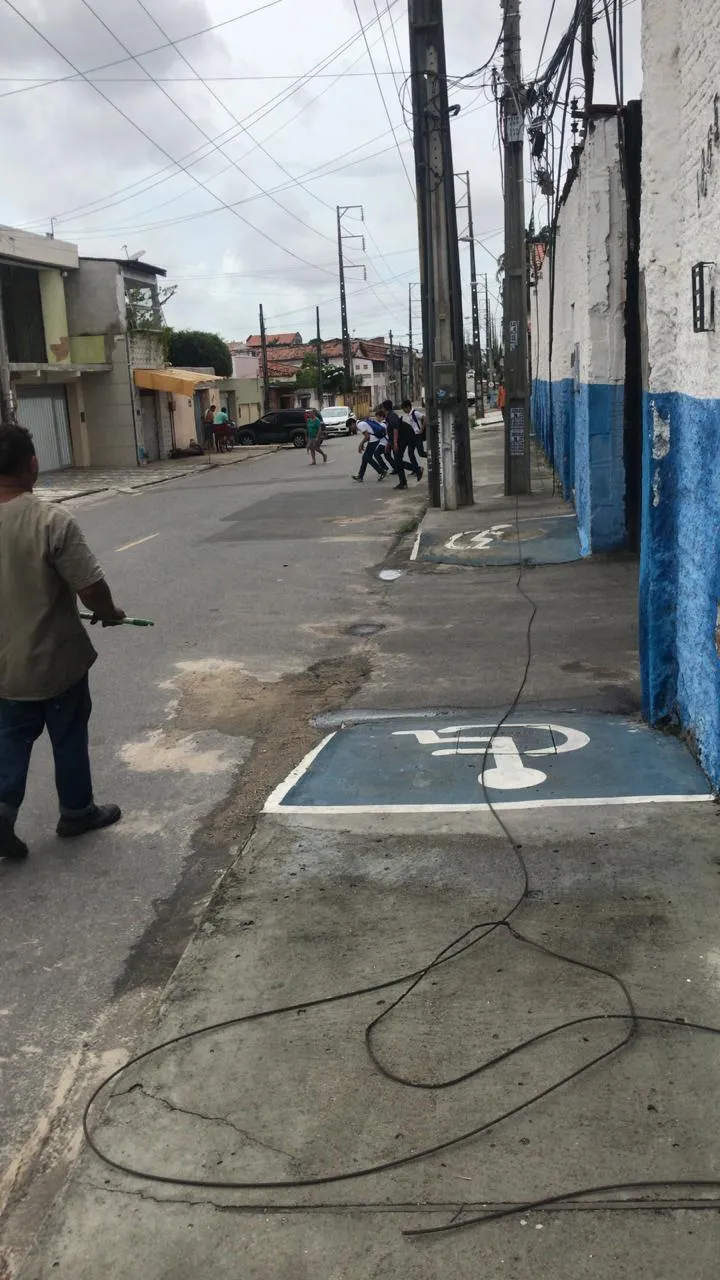 Caminhão arrasta fiação, que fica exposta em calçada próxima à escola