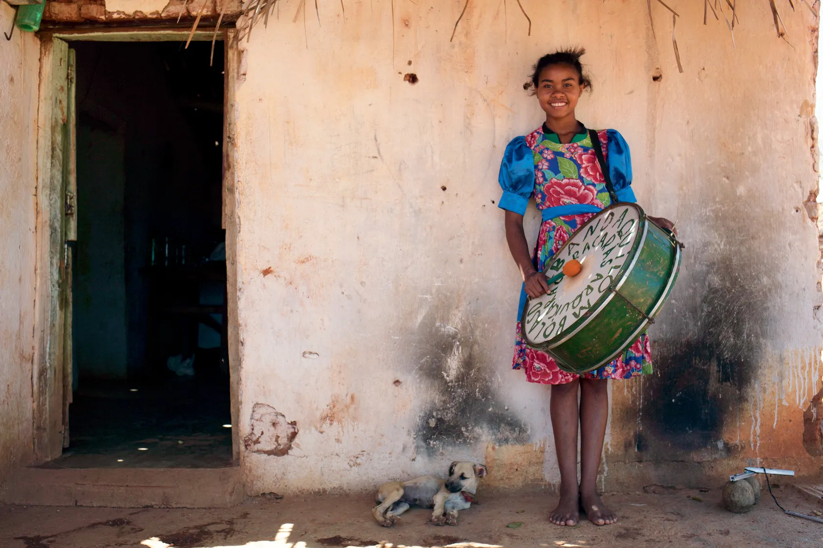 Menina da banda quilombola, acompanhada de cachorro, batuca instrumento