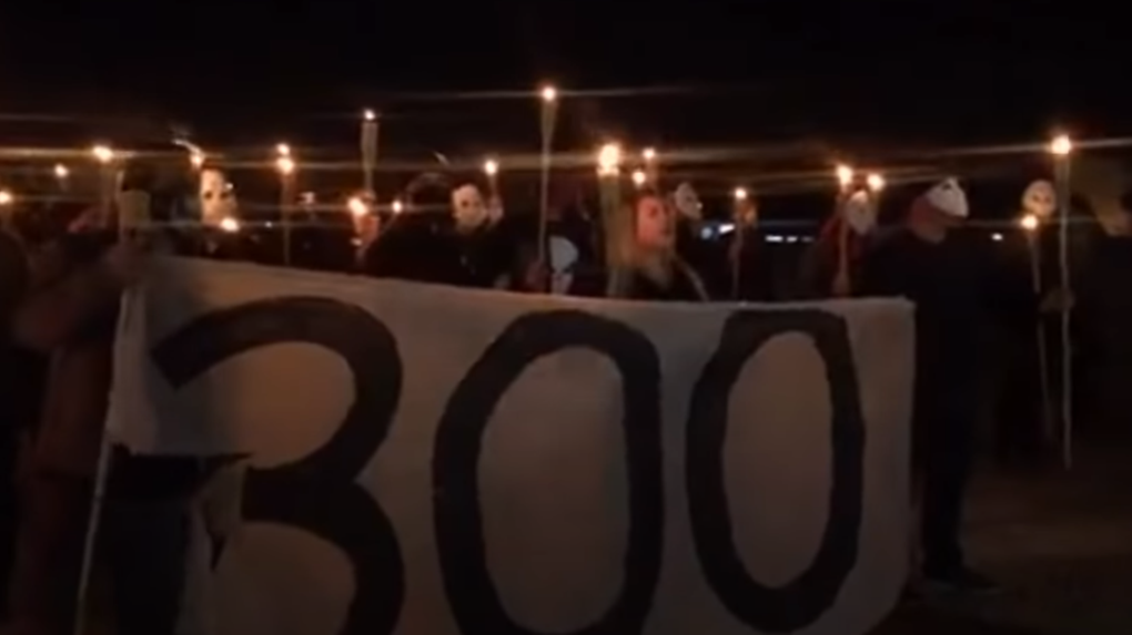 Captura de tela do vídeo de manifestantes com tochas e máscaras durante protesto