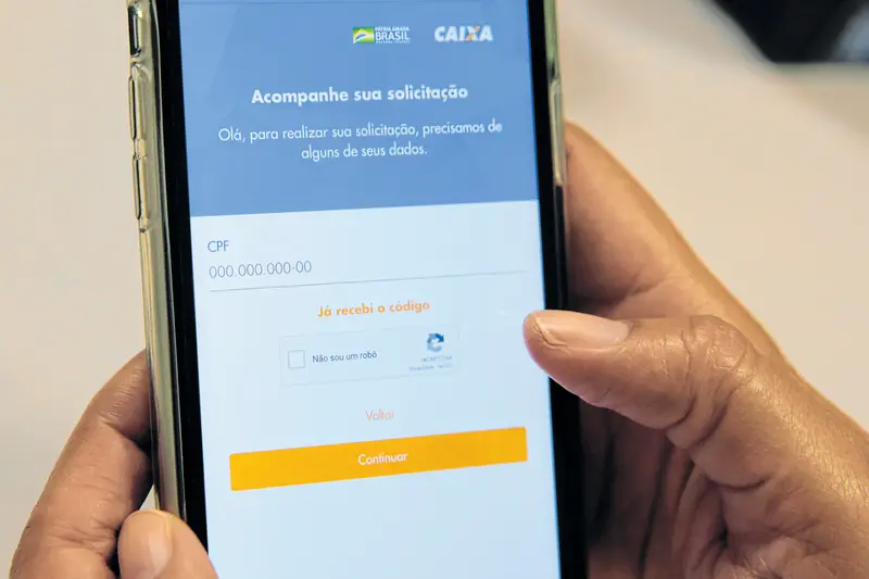 Fotografia de um homem manuseando o celular com o aplicativo Caixa Tem aberto