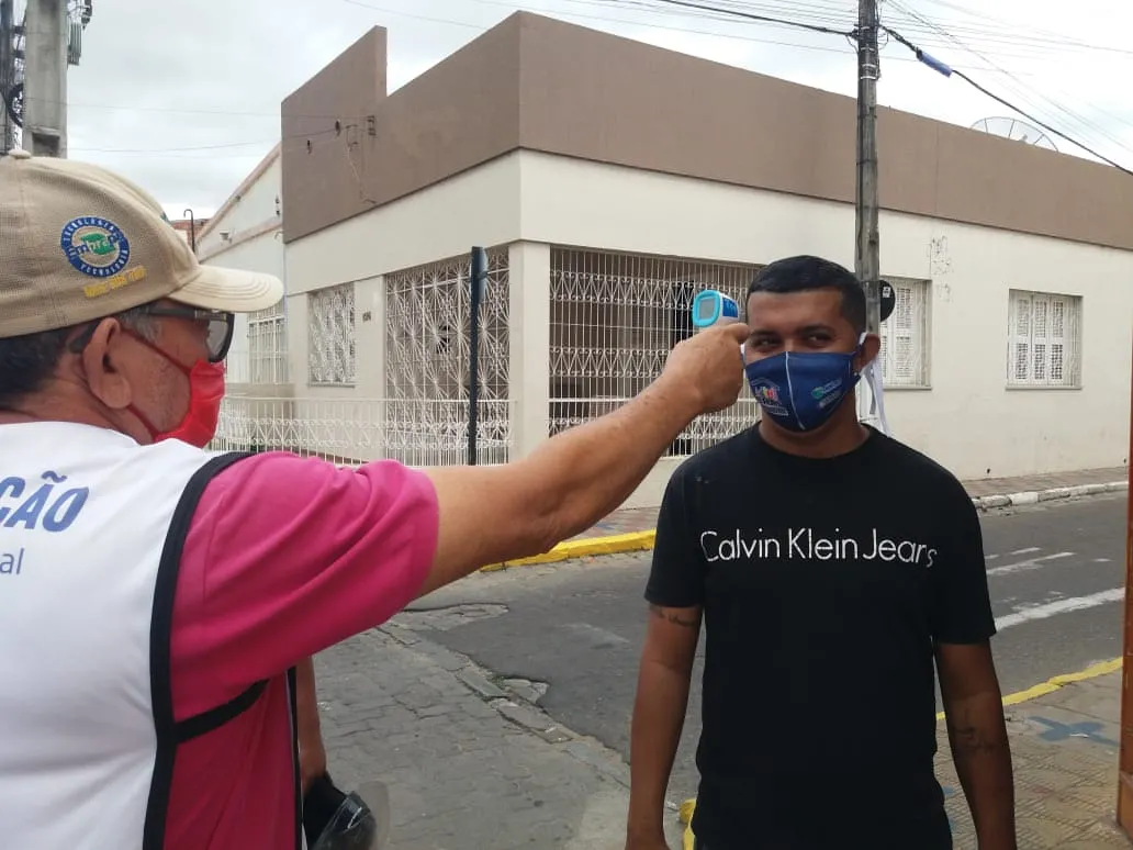 No primeiro dia de abertura de alguns setores, agentes do Município verificam a temperatura corporal de alguns moradores.