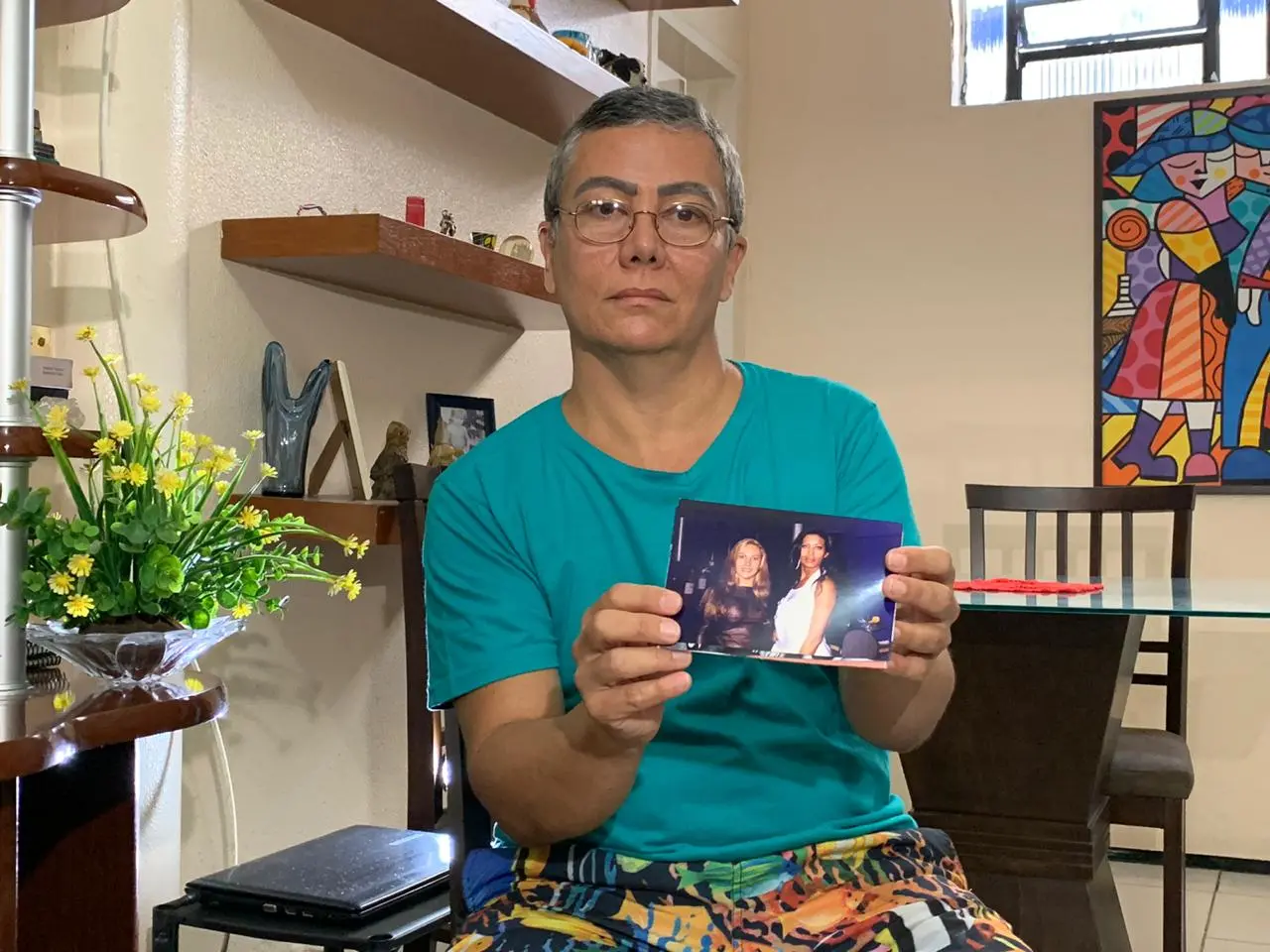 Antônio Teixeira Neto, amigo da vítima, segurando uma foto em que ele aparece, ainda com identidade de travesti, que tinha na época, junto à Manuela