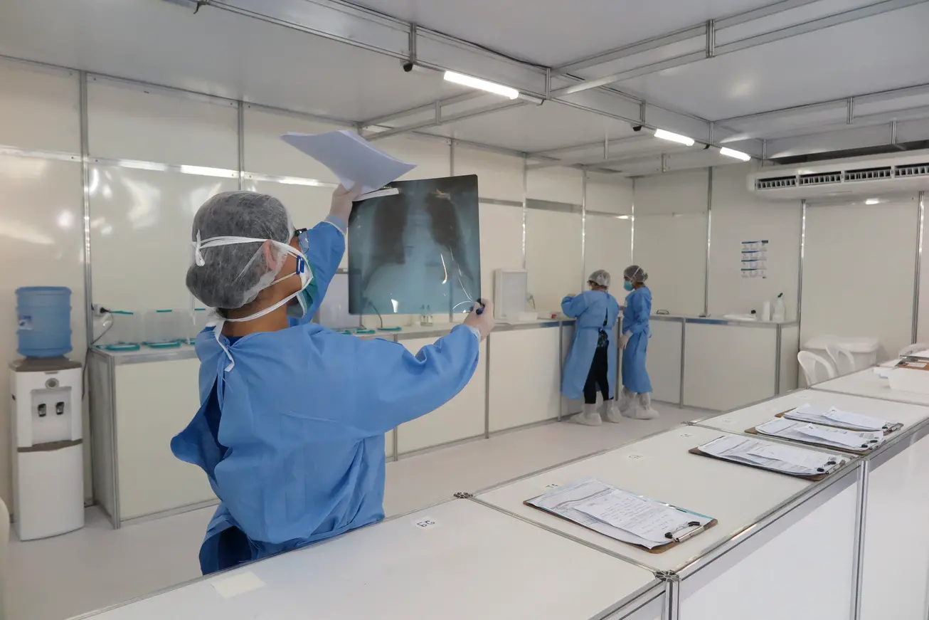 Fotografia de agente de saúde segurando Raio-X