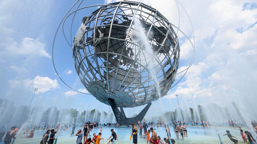 Calor em Nova York, no parque Flushing Meadow Corona Park, no Queens ;AFP People enjoy refreshing water of a fountain in the Unisphere fountain at Flushing Meadow Corona Park in the borough of Queens on July 21, 2019 in New York City. - The US is sweating through a weekend of extremely hot weather, with major cities including New York and Washington bracing for temperatures close to or exceeding 100 degrees Fahrenheit (38 degrees Celsius). (Photo by Johannes EISELE / AFP)