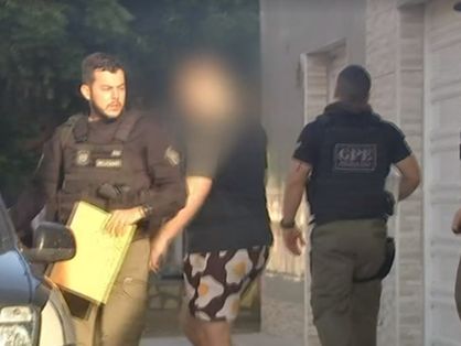 A foto mostra três policiais saindo de uma casa, conduzindo um homem, com o rosto embaçado para evitar a identificação.