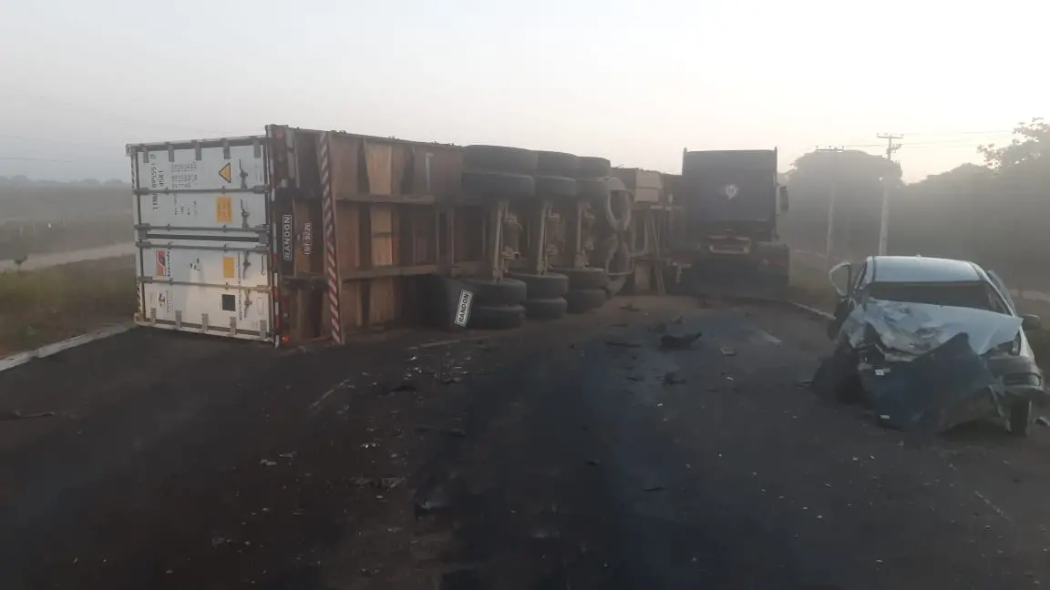 Carreta tombada e carro com a parte frontal amassada no meio da rodovia