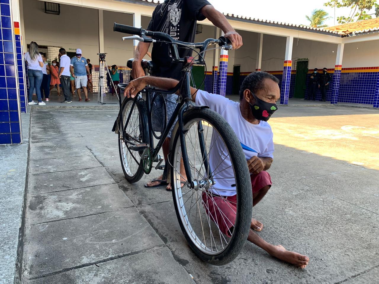 Eleitor com dificuldade de mobilidade sentado no chão ao lado da bicicleta do irmão