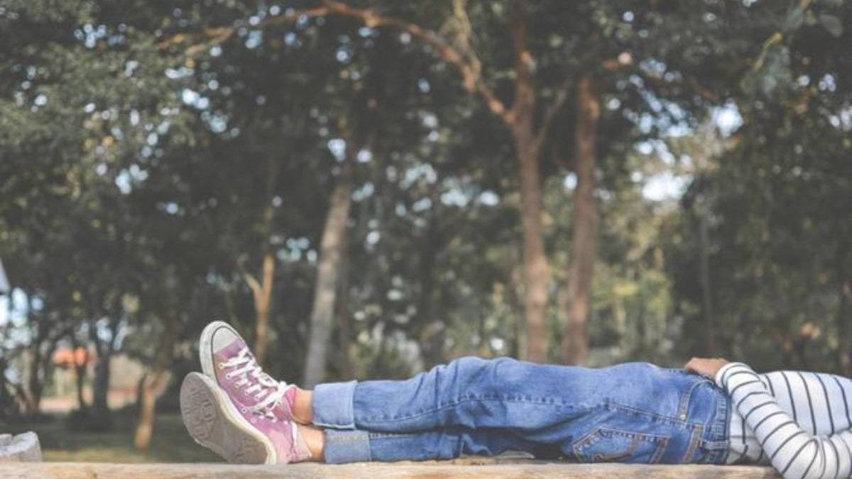 Menina deitada em banco no parque