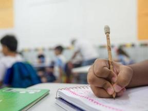 Foto de criança segurando lápis na escola