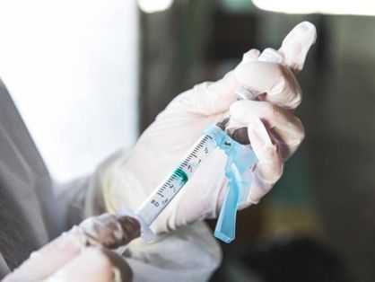 Foto de pessoa segurando seringa de vacina