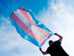 Foto de homem segurando a bandeira trans