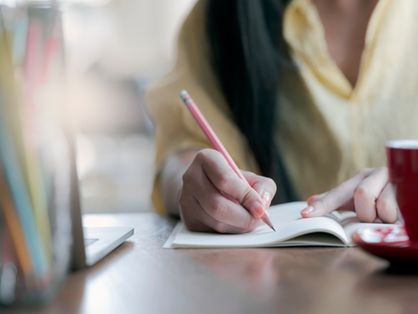 Mulher estudando escrevendo em um caderno