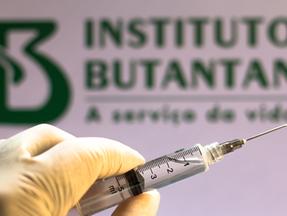Está é uma imagem de uma seringa com a logo do Instituto Butantan como plano de fundo.