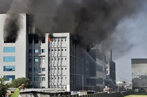 Nesta imagem há o Instituto Indiano de Serum, na Índia, em chamas e bombeiros tentando controlar o incêndio