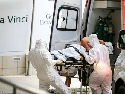 Maqueiros paramentados retiram paciente de ambulância no hospital Leonardo da Vinci em 26/05/2020