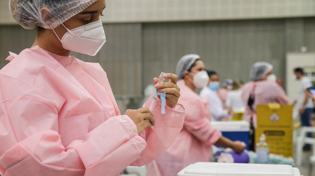 Enfermeira com equipamentos de segurança, como máscara e touca, abastasse uma seringa com vacina contra Covid-19 durante campanha de vacinação de profissionais da saúde no Centro de Eventos, em Fortaleza