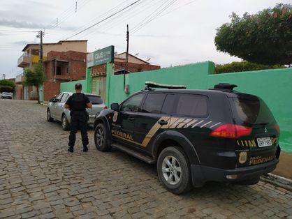 Esta imagem mostra uma viatura da polícia federal estacionada ao lado do CRAS do município de Catarina, no Ceará. Ao lado do automóvel está um agente da Polícia Federal.