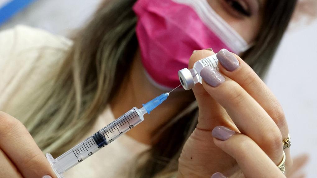 Campanha de vacinação em Israel começou em dezembro, na foto uma mulher segura a vacina contra Covid-19