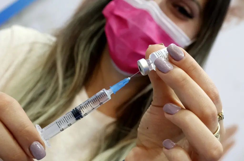 Campanha de vacinação em Israel começou em dezembro, na foto uma mulher segura a vacina contra Covid-19