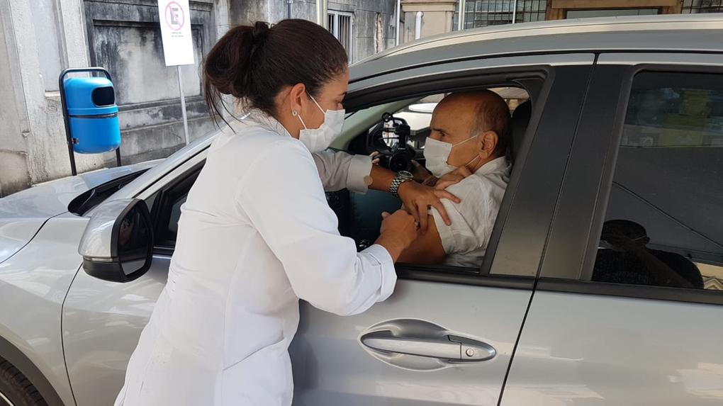 Enfermeira vacinando o médico Drauzio Varella em um carro
