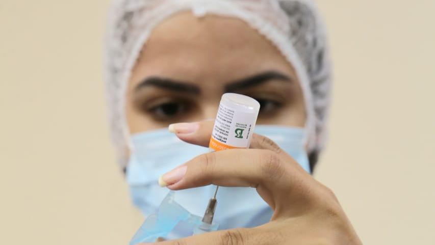 A imagem mostra a enfermeira com a agulha, para aplicar a dose da vacina contra Covid-19