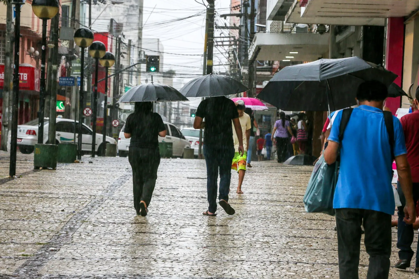 pessoas andando na rua com guarda-chuva