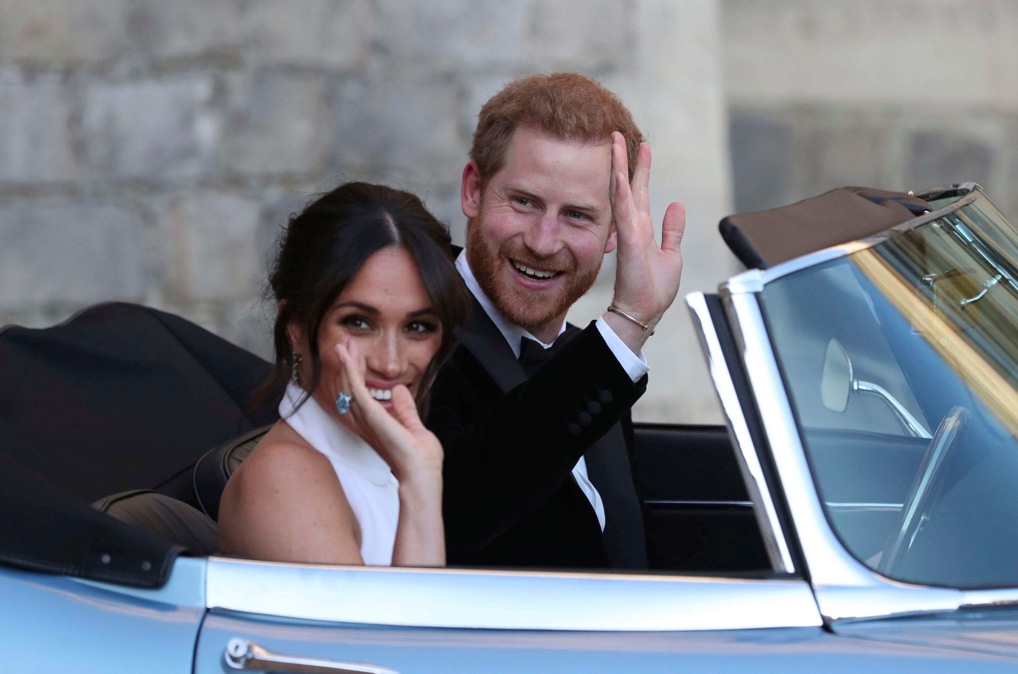 Na foto, o príncipe Harry e Meghan Markle, que renunciaram aos títulos reais, aparecem acenando a bordo de um carro.