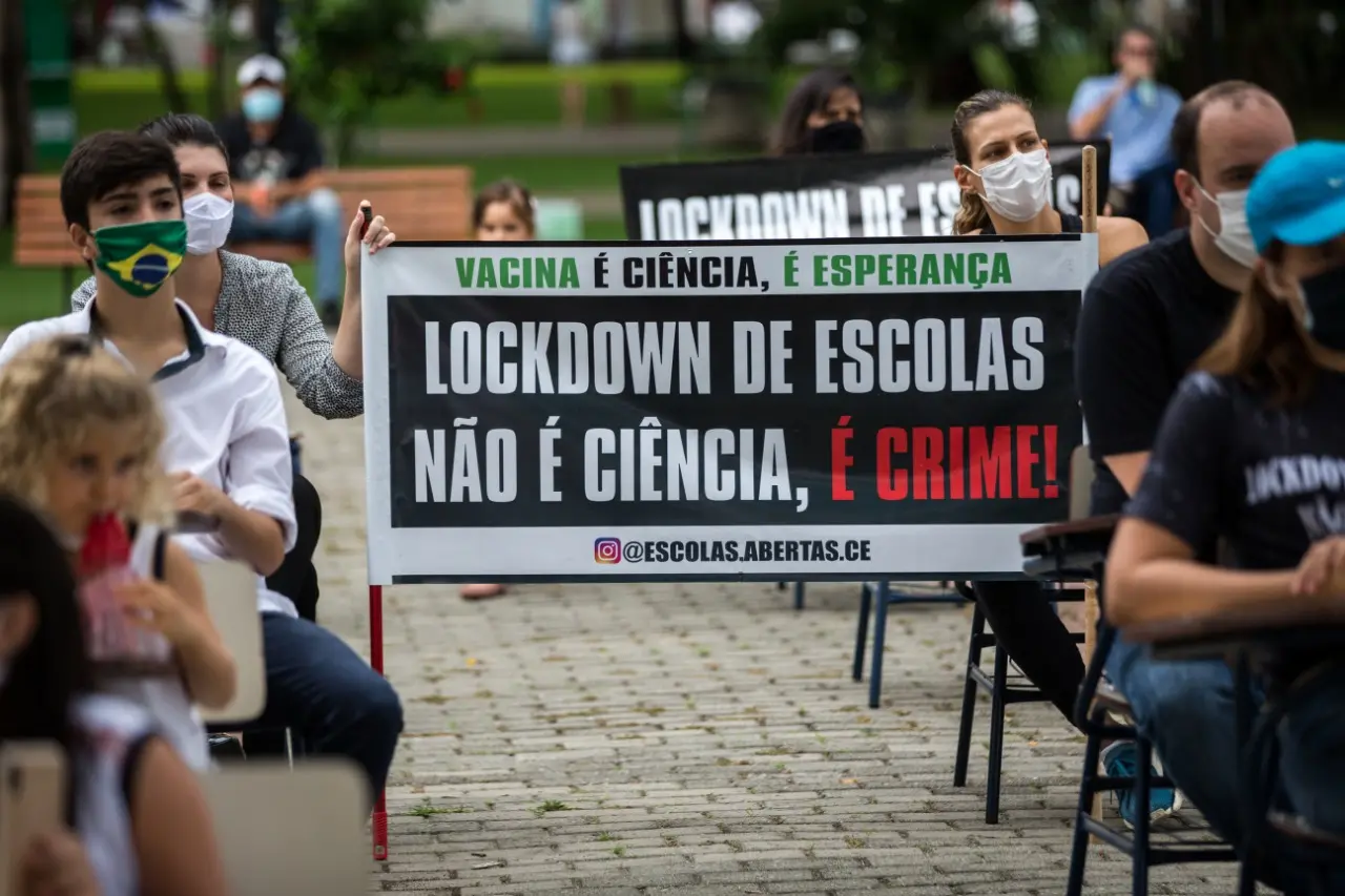 Pais e mães seguram cartaz em protesto na Praça da Imprensa