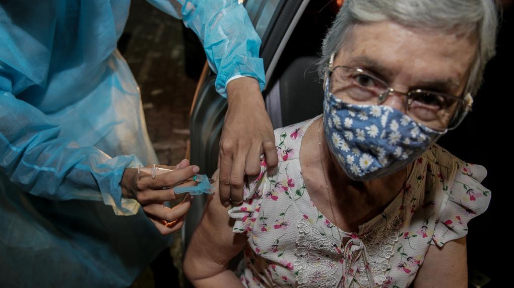 NA FOTO DRIVE THRU IGUATEMI VACINAÇÃO DE IDOSOS. Descritores: campanha de vacinação; idosa sendo vacinada; idosa com máscara; seringa