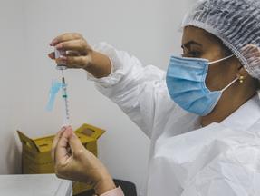 profissional da saúde com máscara; dose de vacina da Covid-19; seringa; pandemia