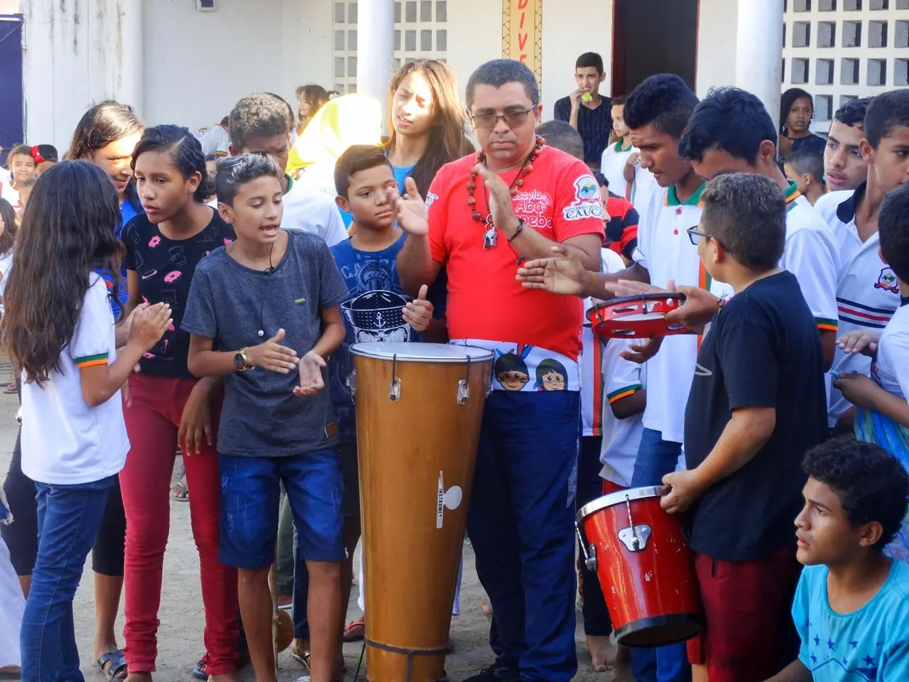 Professor André tocando tambores com alunos da escola Aba Tapeba