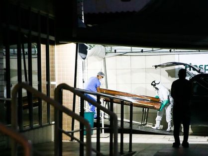 Funcionários carregando caixão de pessoa morta pela Covid-19
