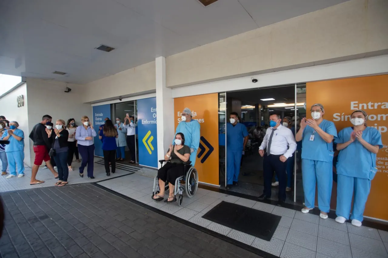 Profissionais da saúde e pacientes assistem a homenagem na frente de hospitais