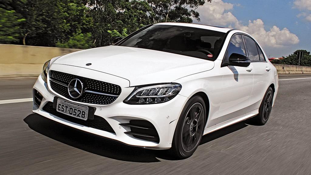 Imagem de um carro modelo Mercedes Benz na cor branca em uma estrada