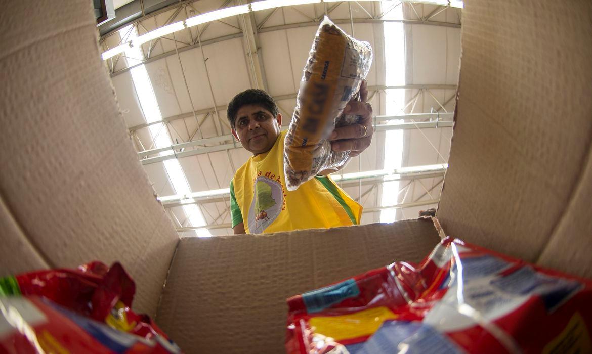 Homem em supermercado reúne itens da cesta básica