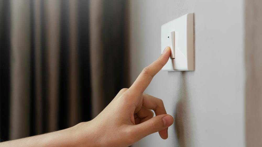 Close-up do dedo feminino está desligado no interruptor de iluminação em casa
