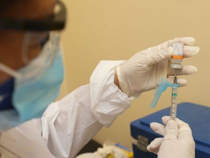 Profissional de saúde manuseia seringa para vacinar